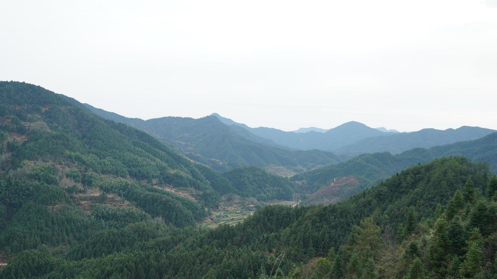 Die schöne Aussicht auf die Berge mit dem grünen Wald und den Wolken, die am regnerischen Tag in der Landschaft des südlichen Chinas aufsteigen? foto