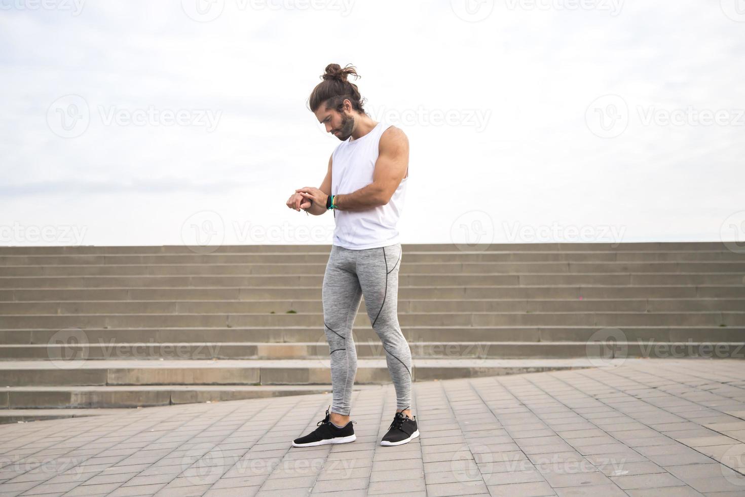 junger Mann mit langen Haaren, der Sportkleidung trägt, die im Freien läuft foto