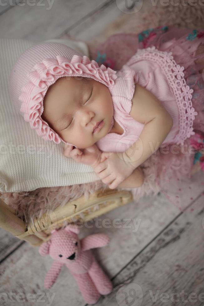 kleines Baby in rosa Kleidung gehüllt mit einem Verband auf dem Kopf liegt schläft auf weißem Kissen foto