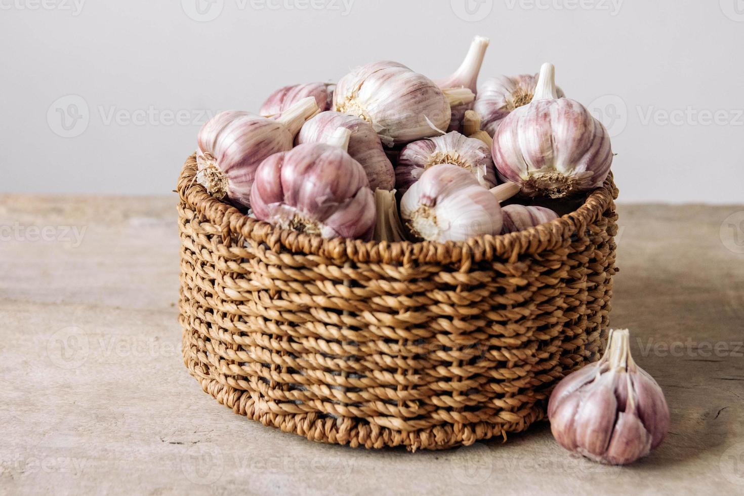 Knoblauch in einem Weidenkorb auf einem Holztischhintergrund foto