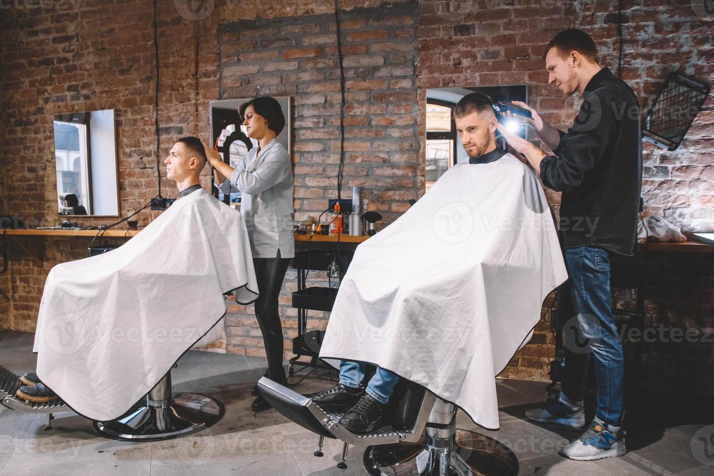 Friseure schneiden ihre Kunden im Friseursalon. Werbe- und Friseurkonzept foto