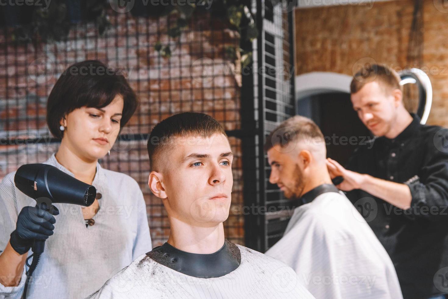 Friseure schneiden ihre Kunden im Friseursalon. Werbe- und Friseurkonzept foto