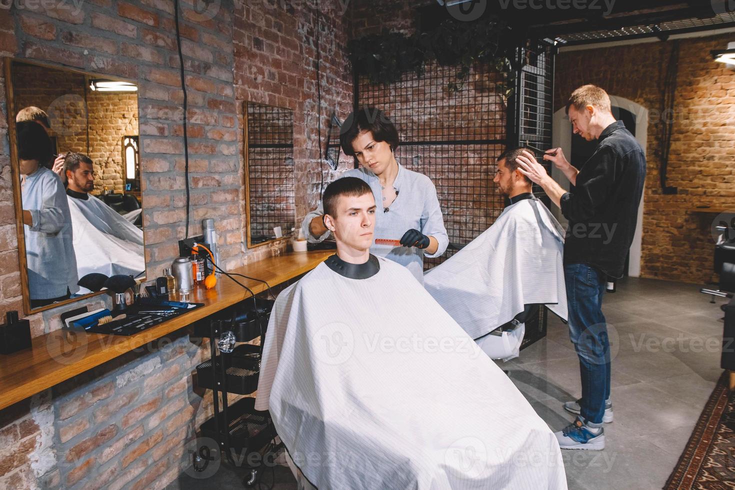 Friseure schneiden ihre Kunden im Friseursalon. Werbe- und Friseurkonzept foto