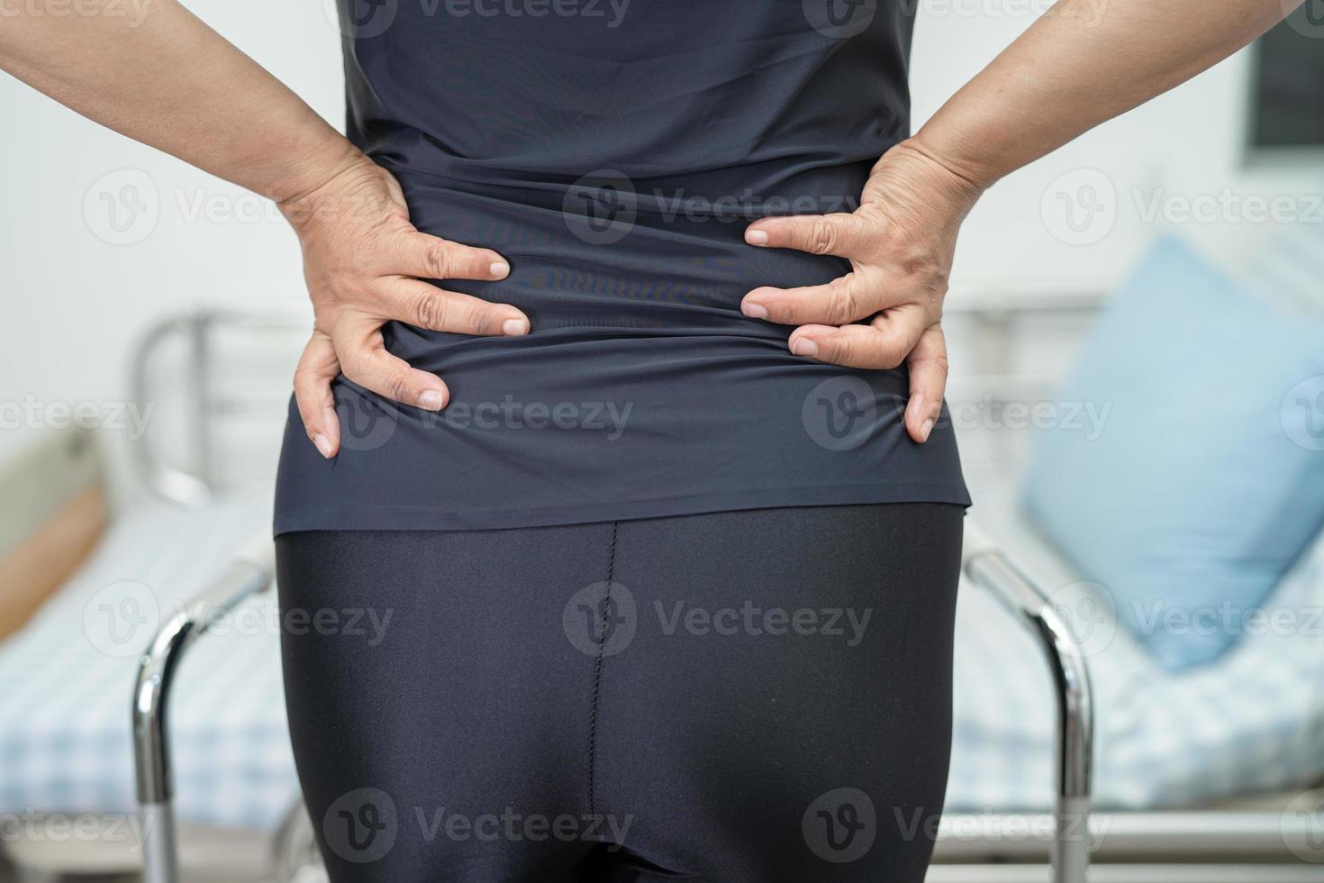 asiatische Patientin schmerzt Rücken, Taille und orthopädische Lendenwirbelsäule mit Gehhilfe. foto