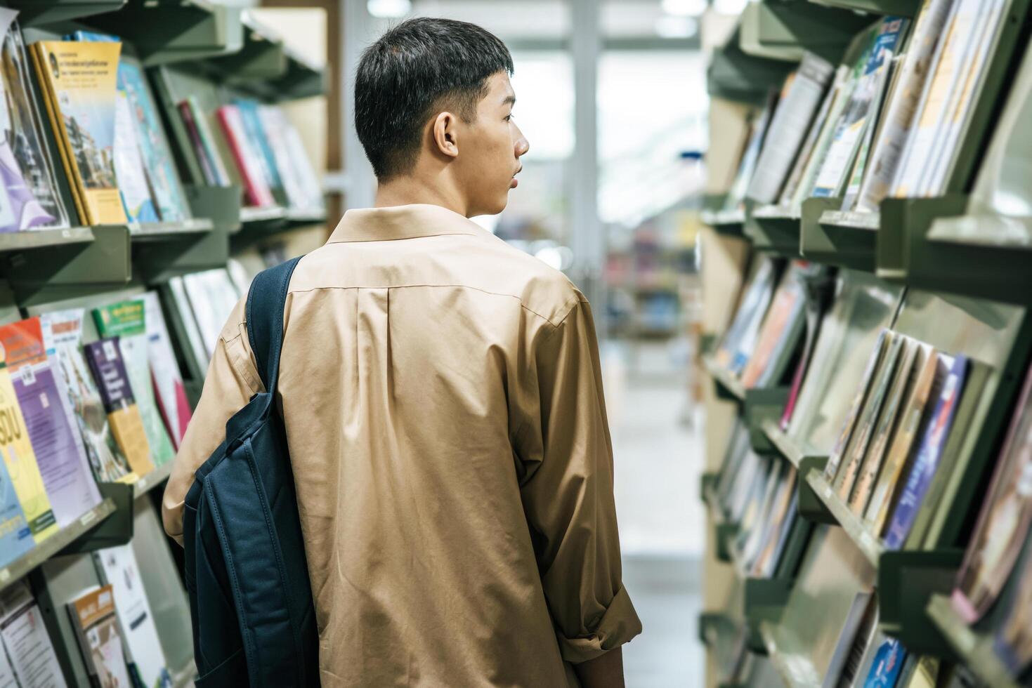 Männer, die einen Rucksack tragen und in der Bibliothek nach Büchern suchen. foto