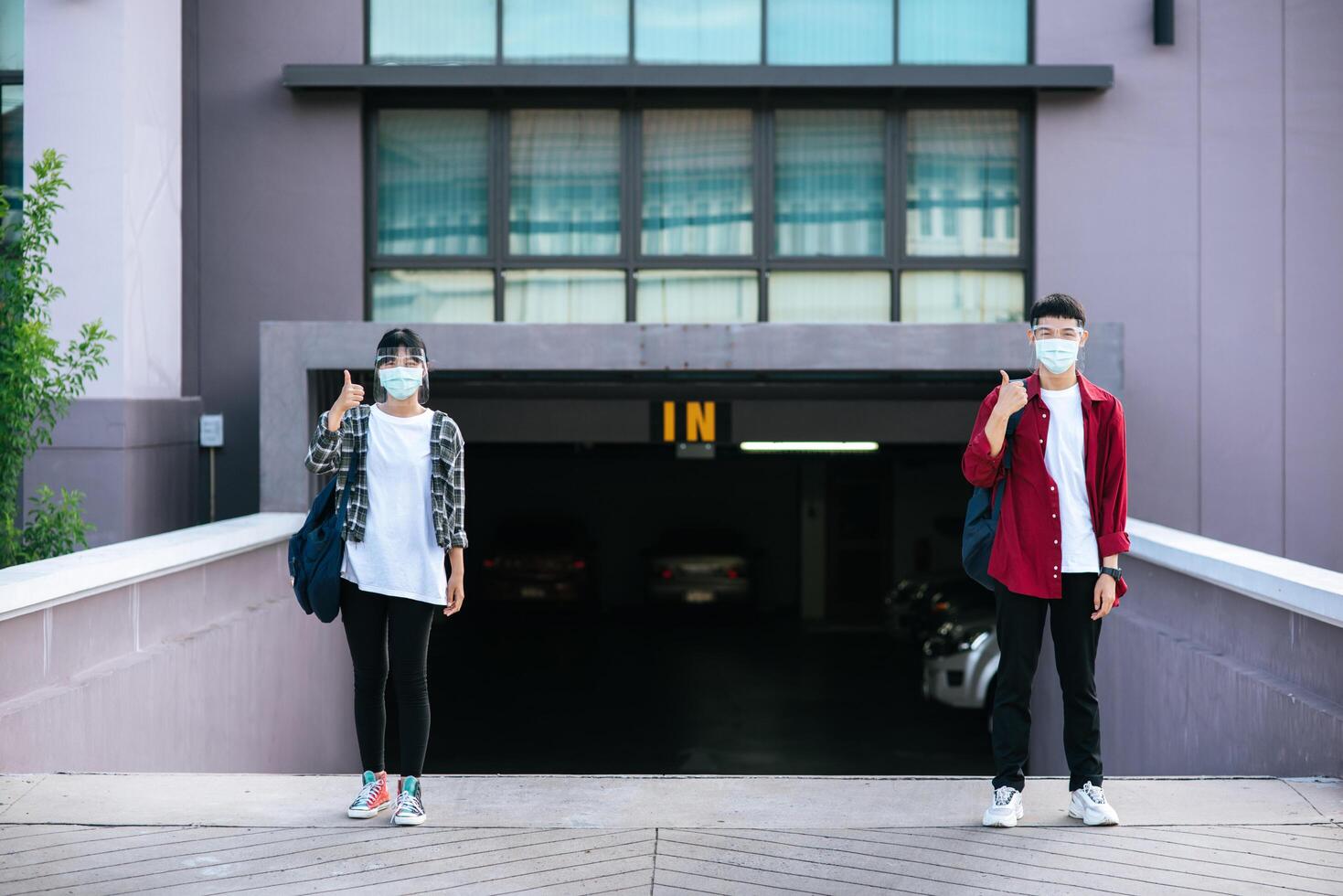 Studentinnen und Studenten tragen Masken und stehen vor der Universität. foto