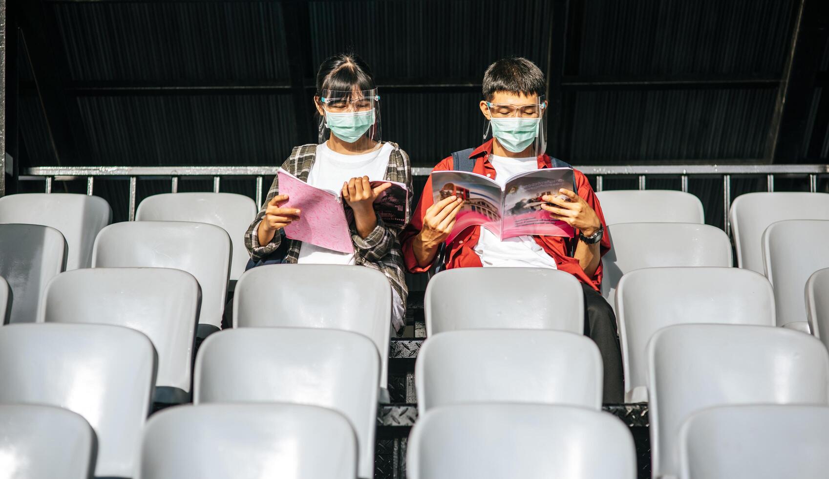 Schülerinnen und Schüler tragen Masken und sitzen und lesen auf dem Feldstuhl foto