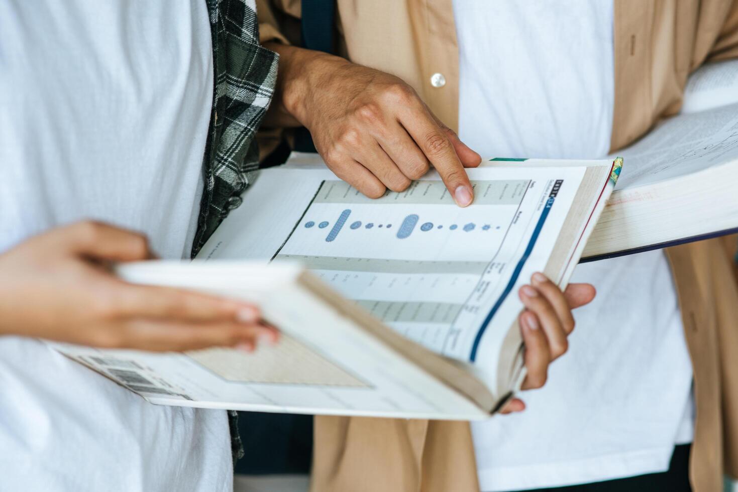 Männer und Frauen mit Masken stehen und lesen in der Bibliothek. foto