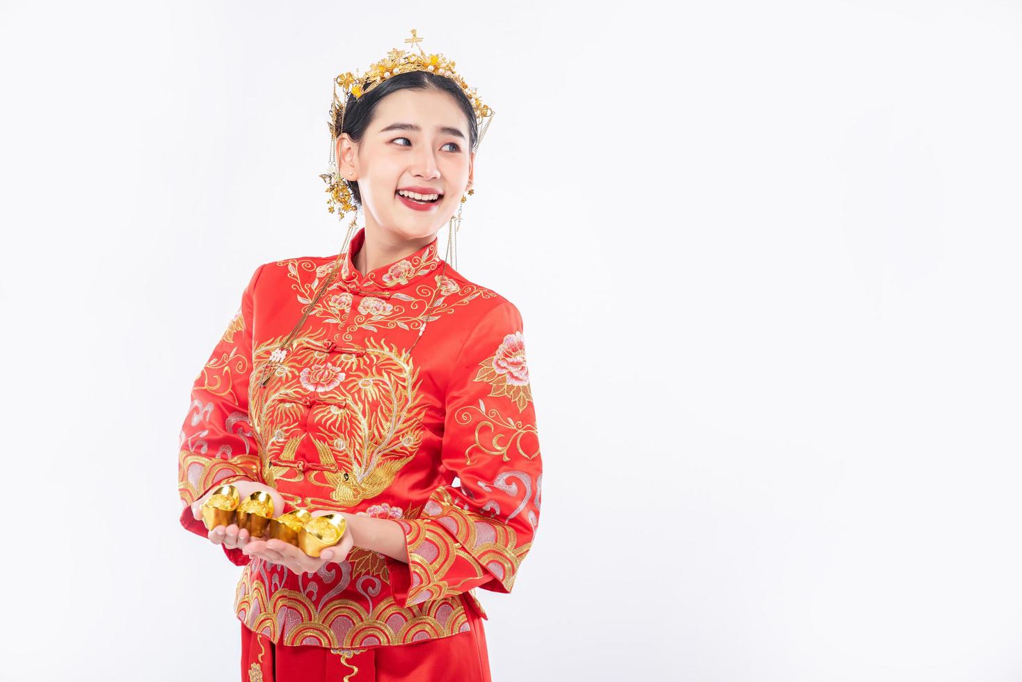 Frau trägt Cheongsam-Anzug mit Krone, die froh ist, ihrer Familie Gold zum Glück im chinesischen Neujahr zu schenken foto
