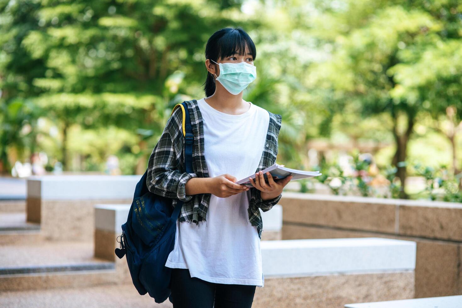 Studentinnen tragen Masken, stehen auf Treppen und halten Bücher. foto