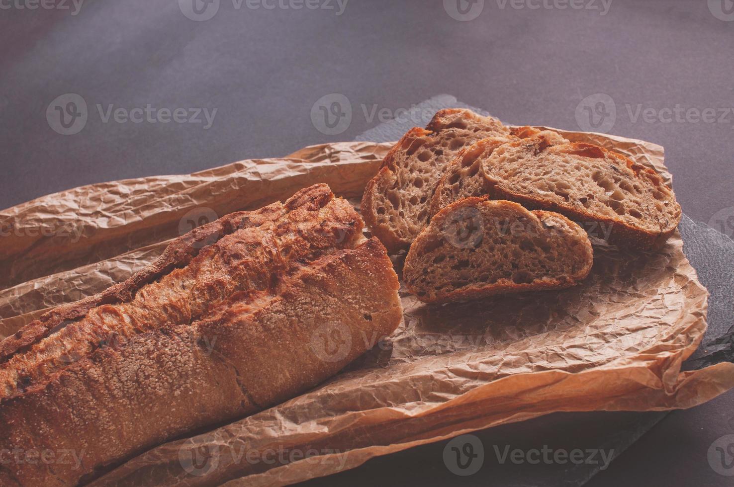 rustikales Brot, schöne goldene Kruste, geschnittenes Brot auf schwarzem Brett liegend foto