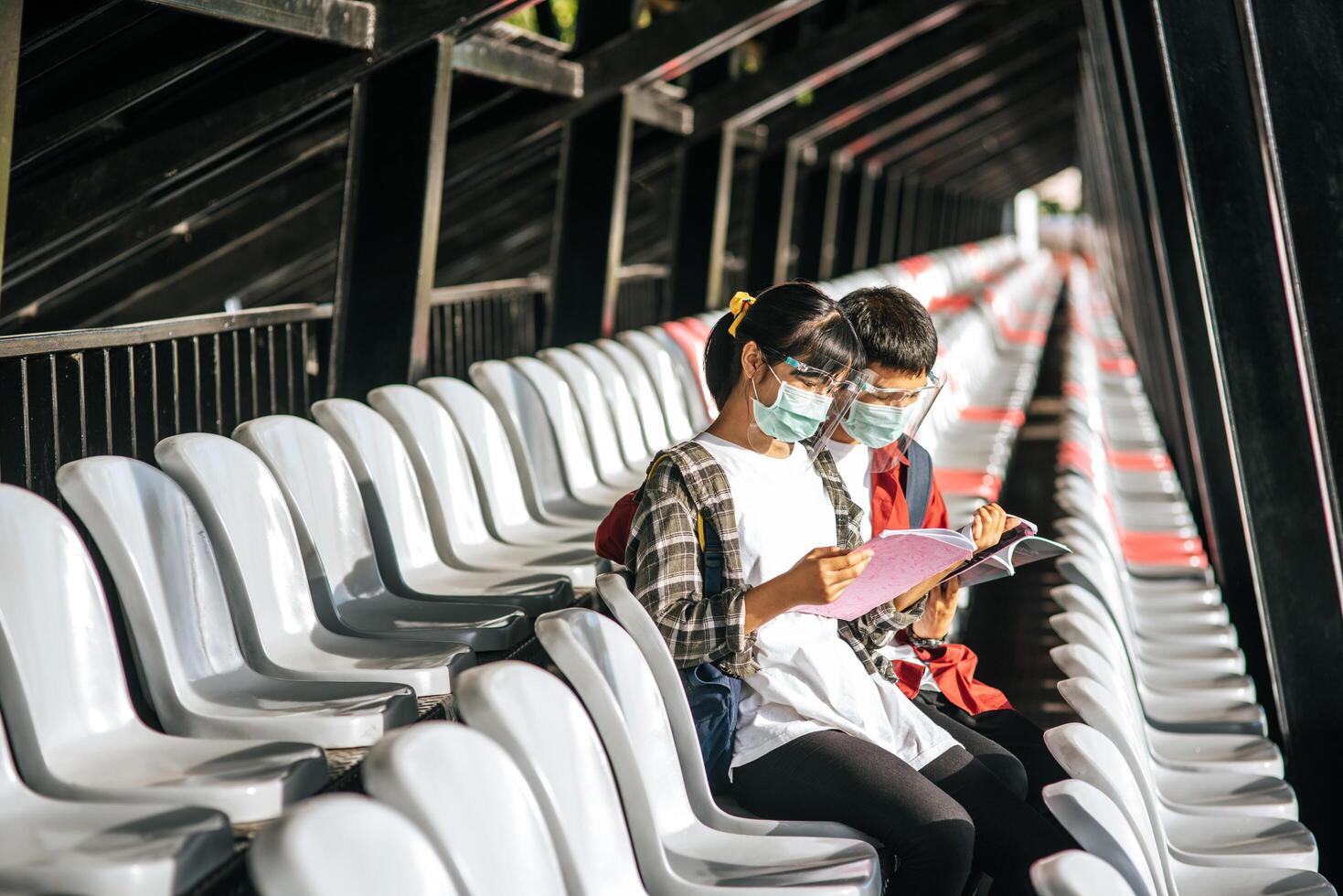 Schülerinnen und Schüler tragen Masken und sitzen und lesen auf dem Feldstuhl foto