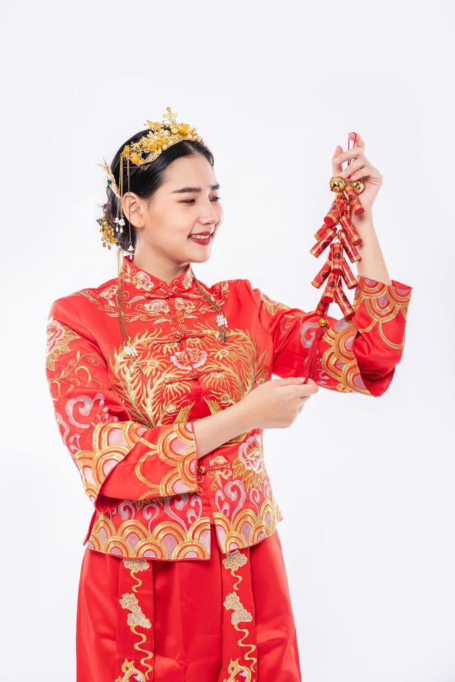 Frau trägt Cheongsam-Anzug Lächeln, um Feuerwerkskörper von Verwandten im chinesischen Neujahr zu bekommen foto