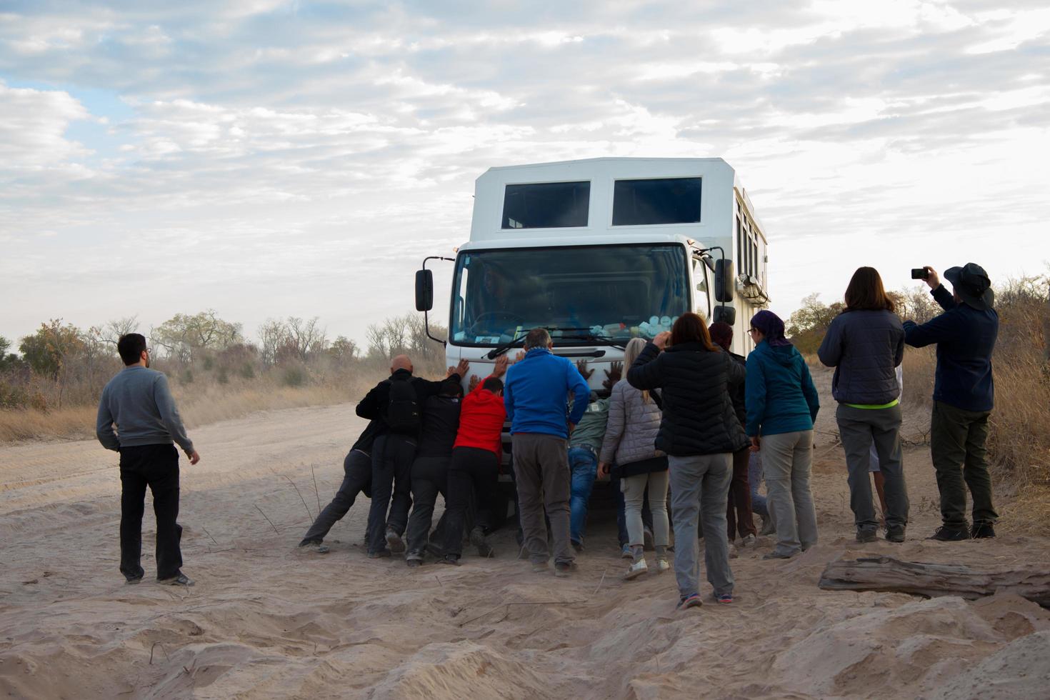 Kalahari-Wüste, Namibia, 2016, Gruppe von Touristen, die ihrem LKW helfen, durch eine sandige Straße zu kommen. bewölkter Himmel, Kopienraum. Kalahari-Region, Namibia foto