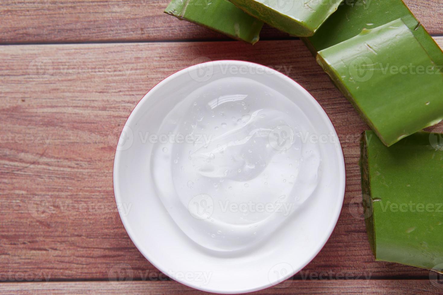 frische Aloe Vera in Scheiben geschnitten und flüssiges Gel in Plastikbehälter auf weißem Hintergrund foto