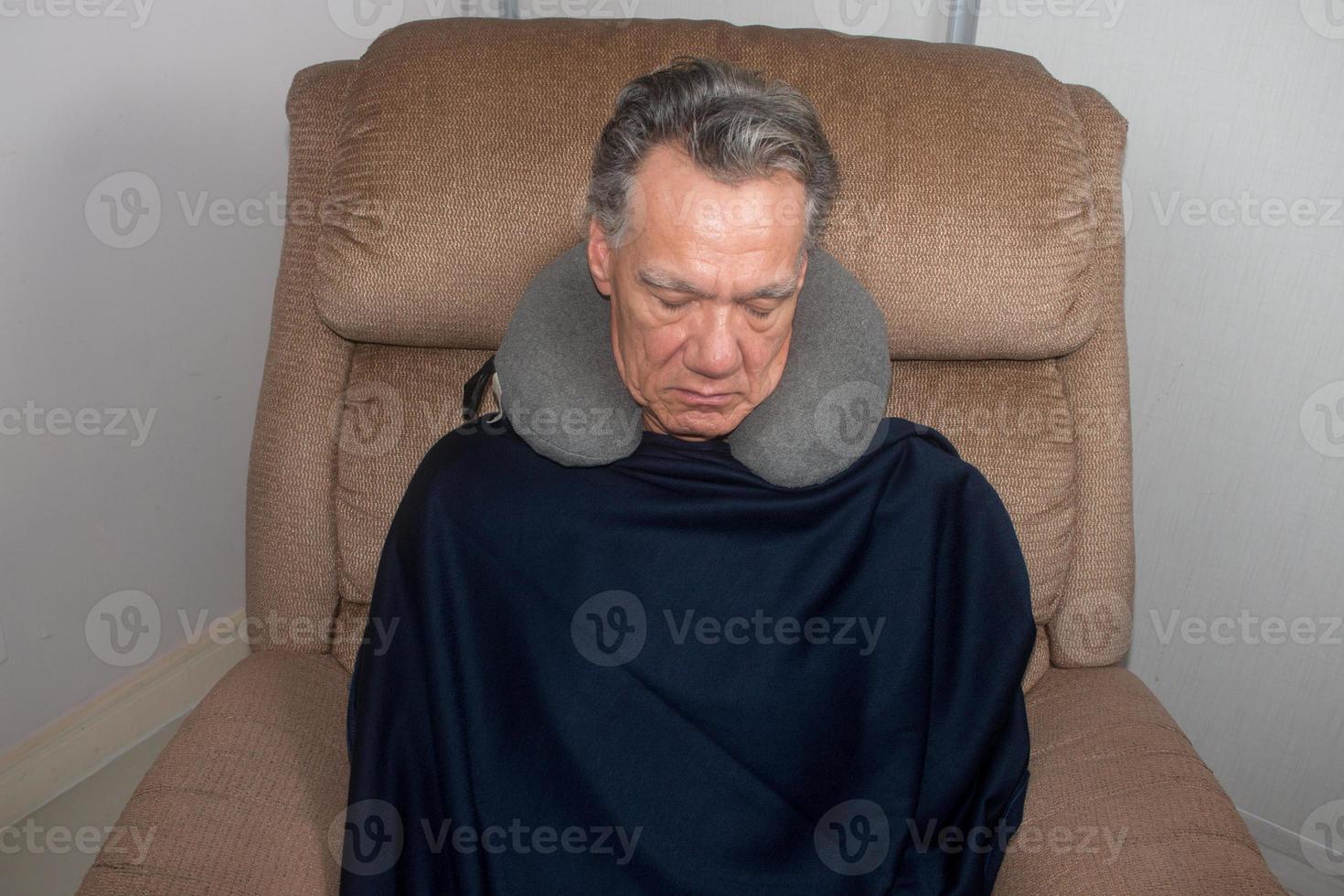 reifer Mann, der mitten am Tag in einem Sessel ein Nickerchen macht foto