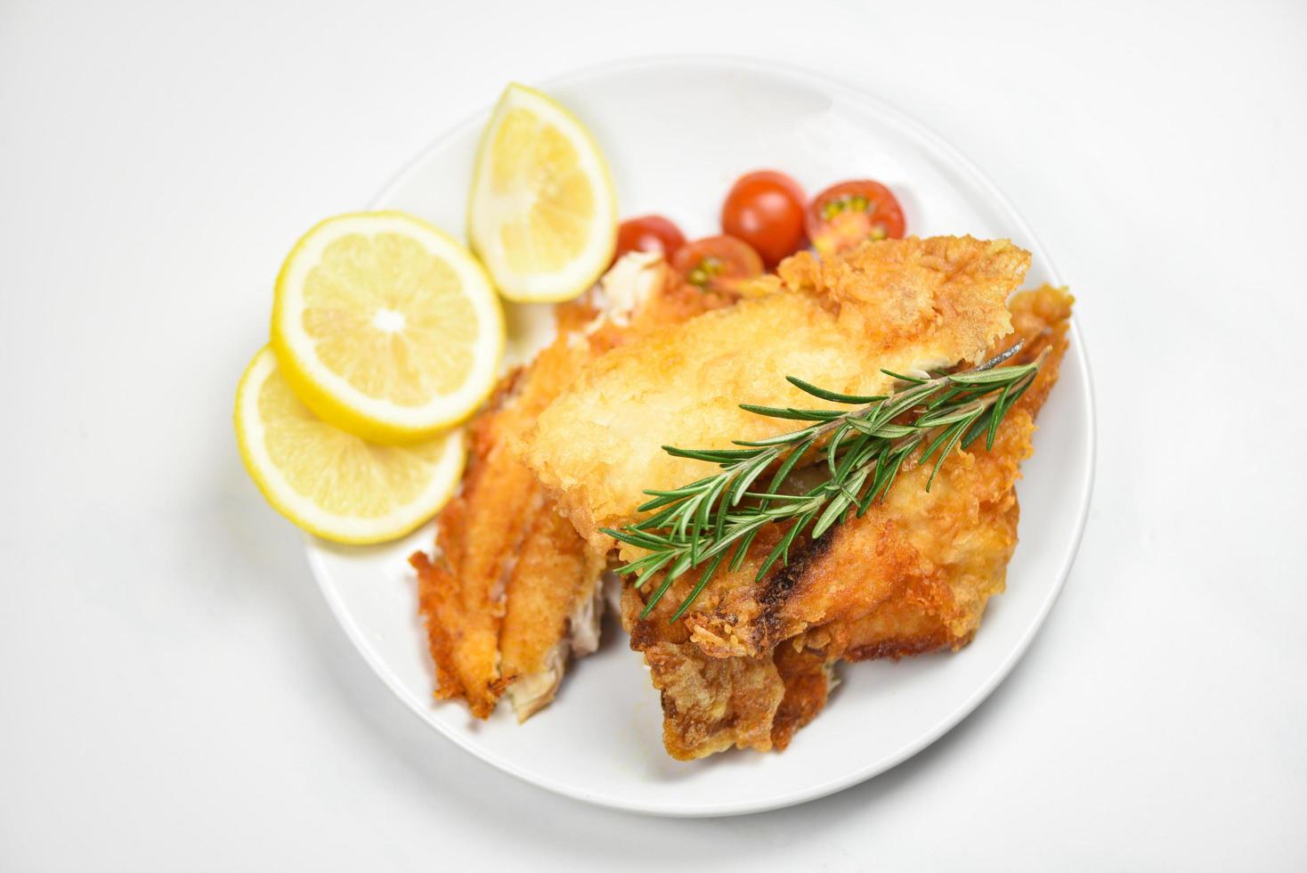 gebratenes Fischfilet in Scheiben geschnitten für Steak oder Salat Kochen mit Kräutern Gewürzen Rosmarin und Zitrone Tilapiafilet Fisch knusprig serviert auf weißem Teller foto