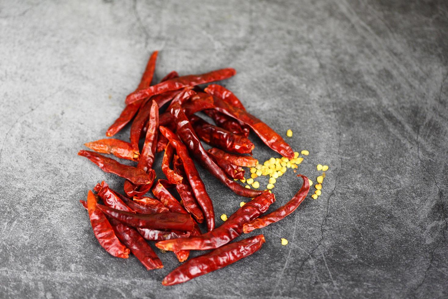 getrocknete Chilis auf dunklem Hintergrund - rote Chilisamen foto