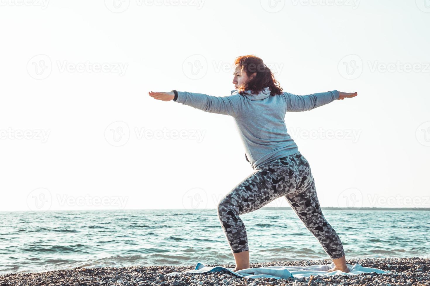 Mädchen macht Yoga und streckt sich am Strand foto