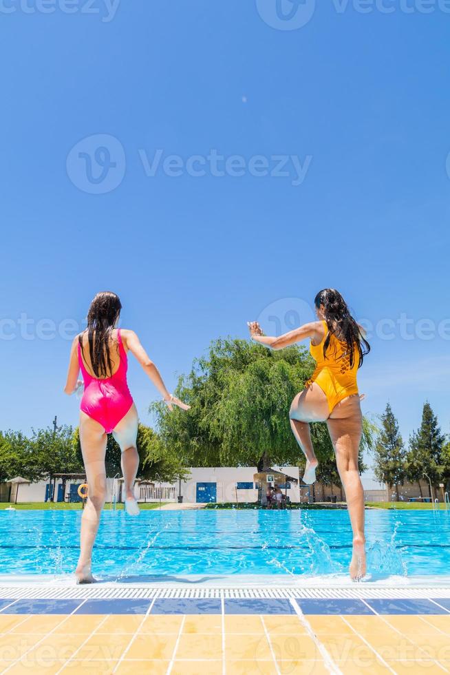Zwei junge Mädchen springen in den Pool. Sommer beginnt Konzept. Platz kopieren foto