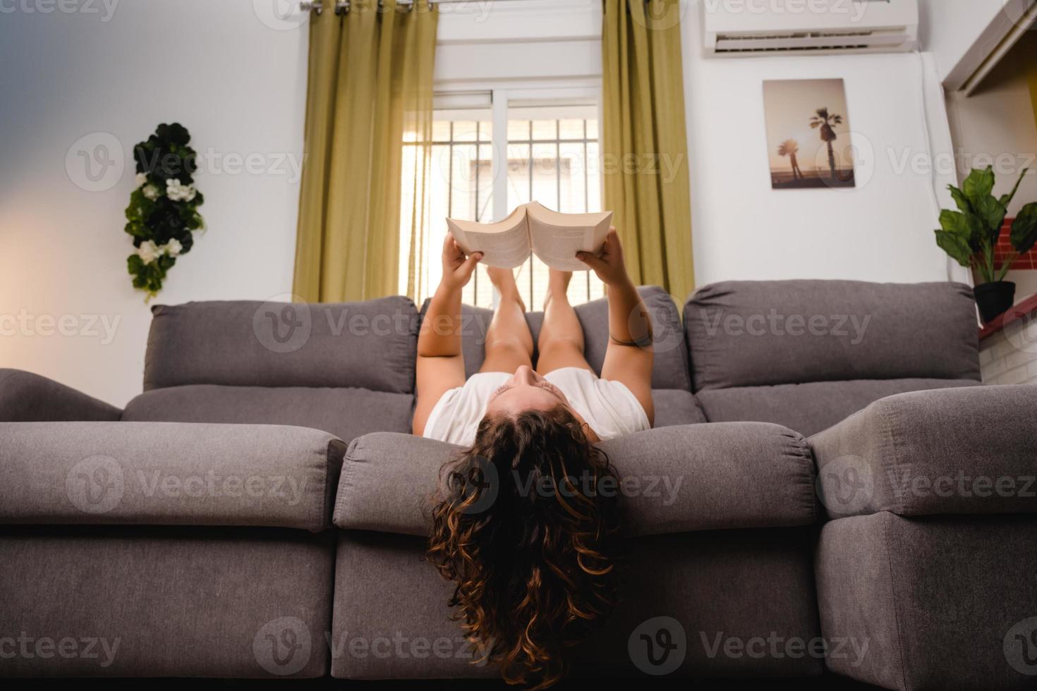 Frau liest ein Buch im Wohnzimmer auf der Couch sitzend foto