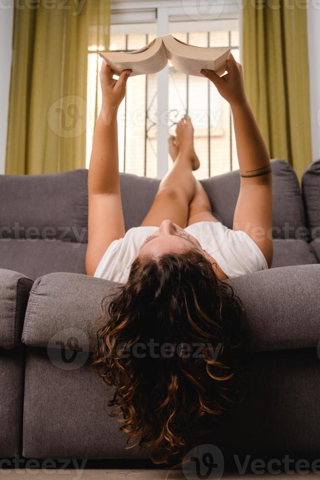 Frau liest ein Buch im Wohnzimmer auf der Couch sitzend foto