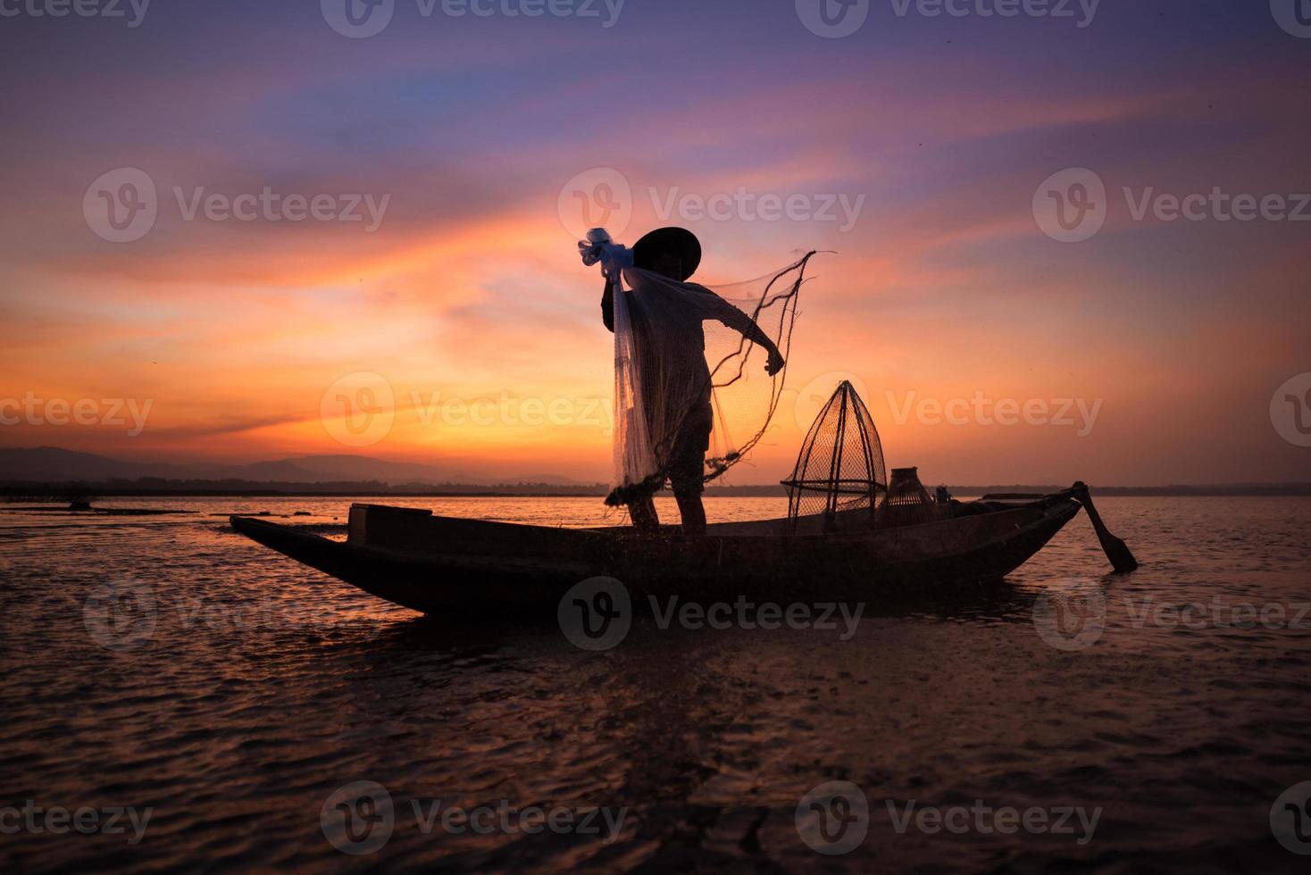 asiatischer Fischer mit seinem Holzboot im Naturfluss am frühen Morgen vor Sonnenaufgang foto