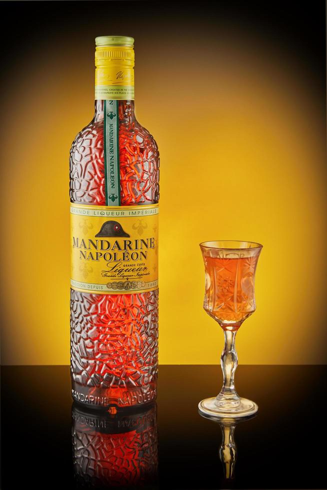 französischer likör mandarine napoleon mit glas auf dunklem hintergrund mit reflexion. foto