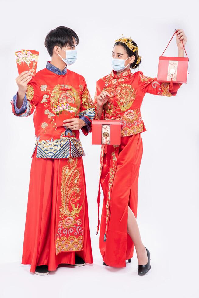 Männer und Frauen tragen Cheongsam Willkommen bei - Holen Sie sich Geschenkgeld und eine rote Tasche für den traditionellen Tag foto