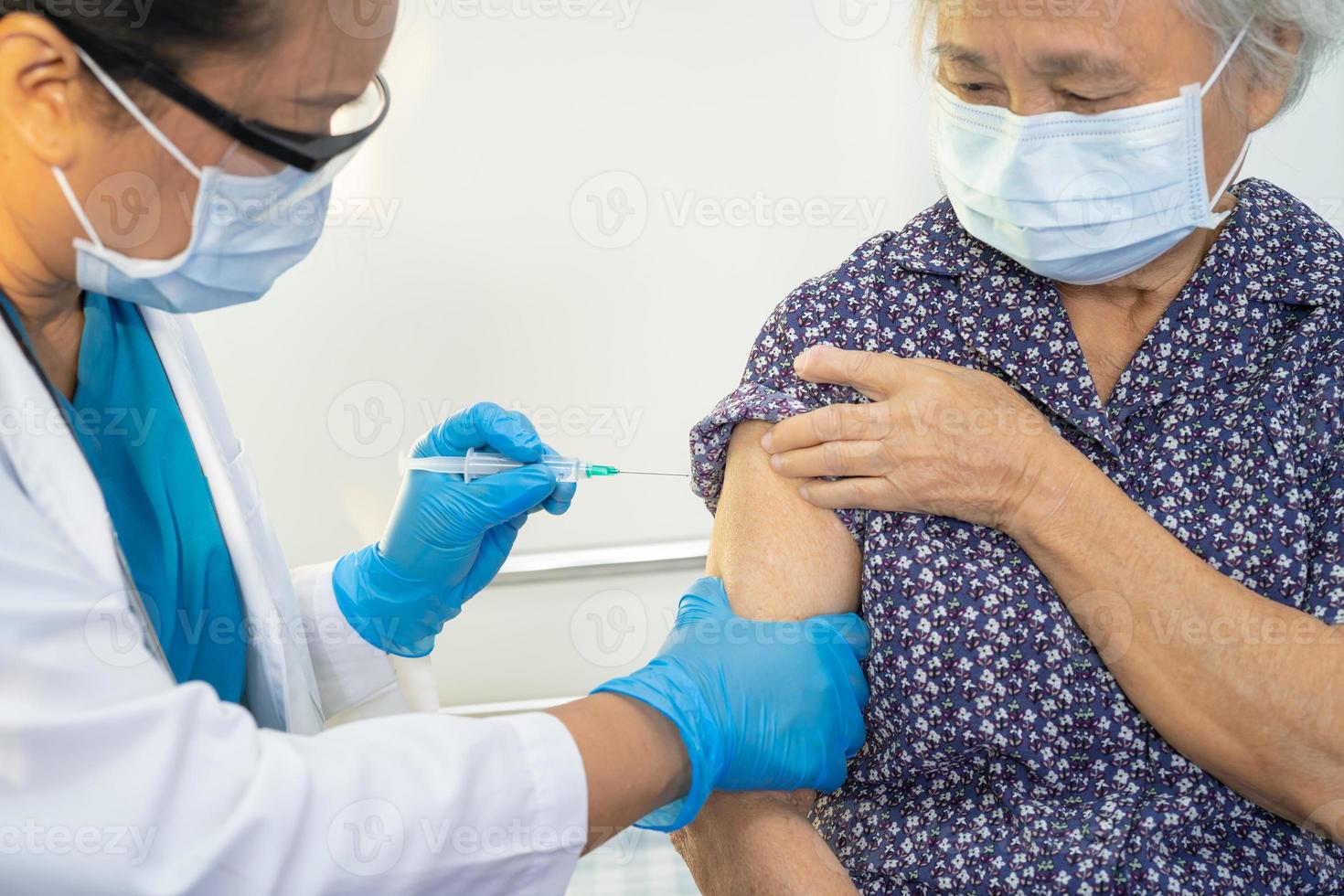 ältere asiatische seniorin mit gesichtsmaske, die vom arzt gegen covid-19 oder coronavirus-impfstoff injiziert wird. foto