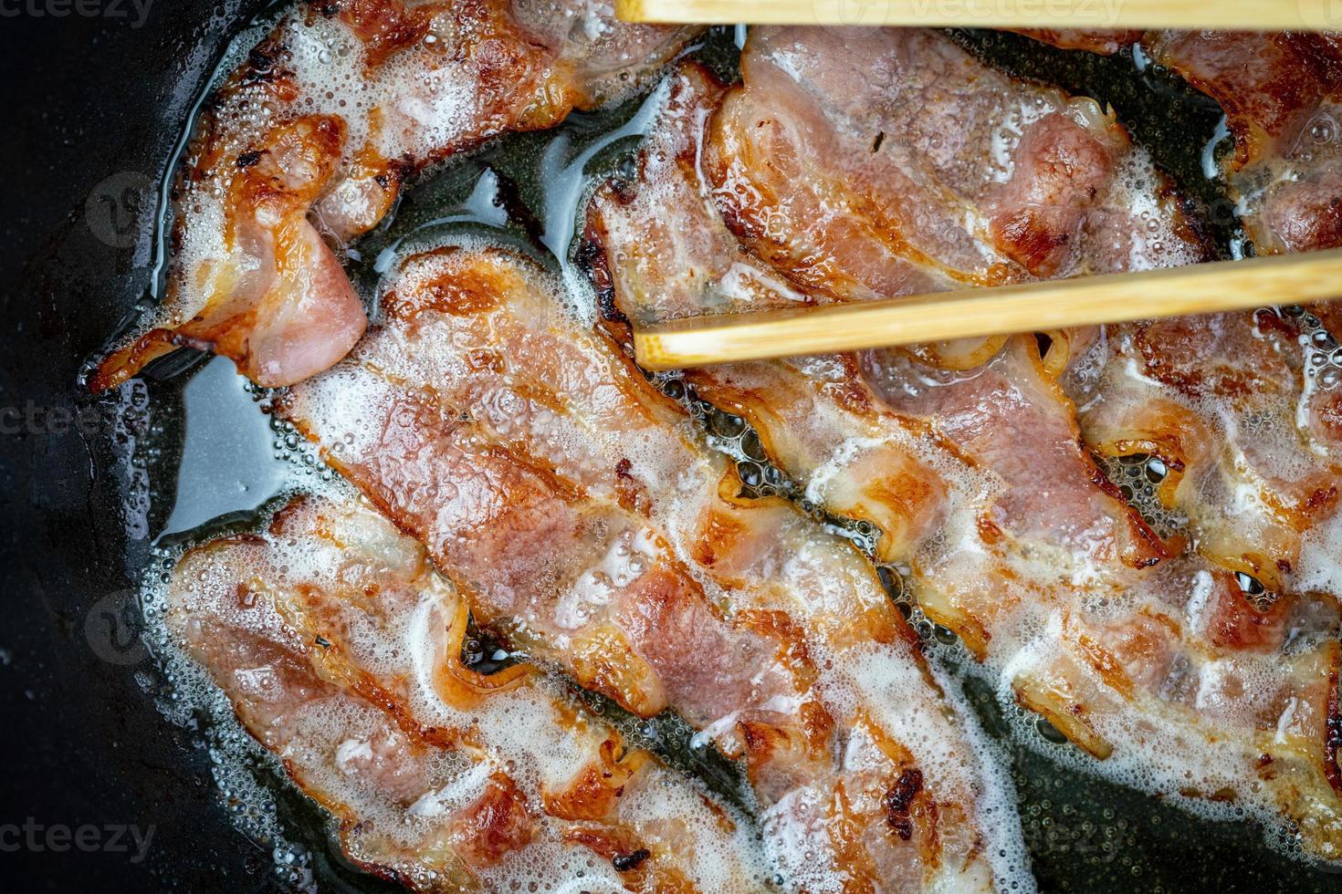 Speck in einer vorgeheizten Pfanne anbraten. Ansicht von oben. foto