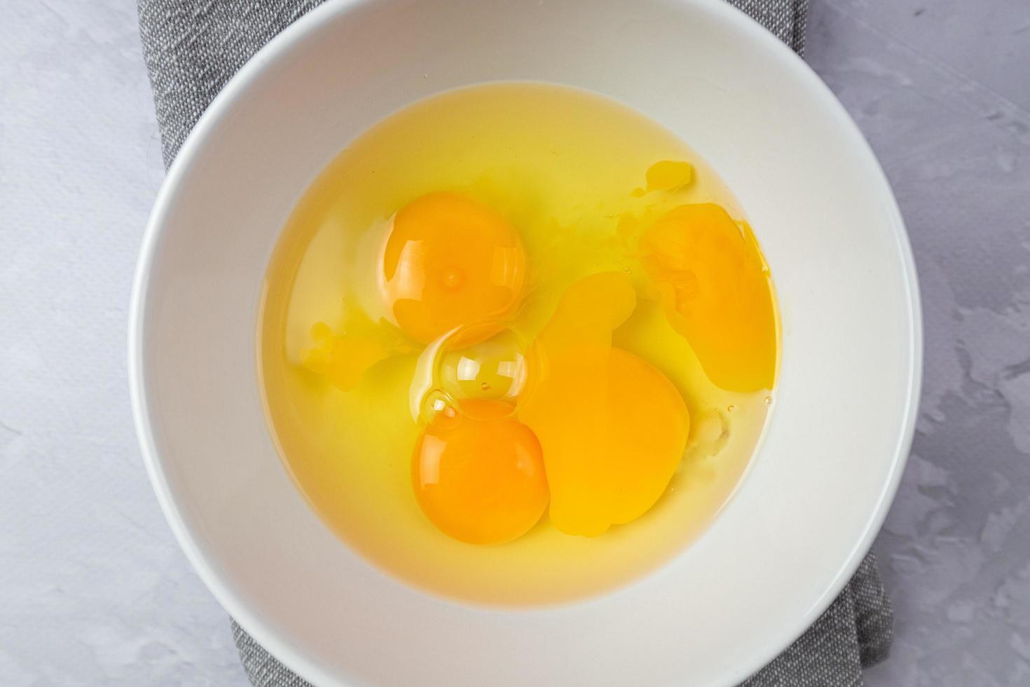 rohe Eier in einer weißen Schüssel. Zubereitung der Zutaten zum Kochen. Ansicht von oben. foto