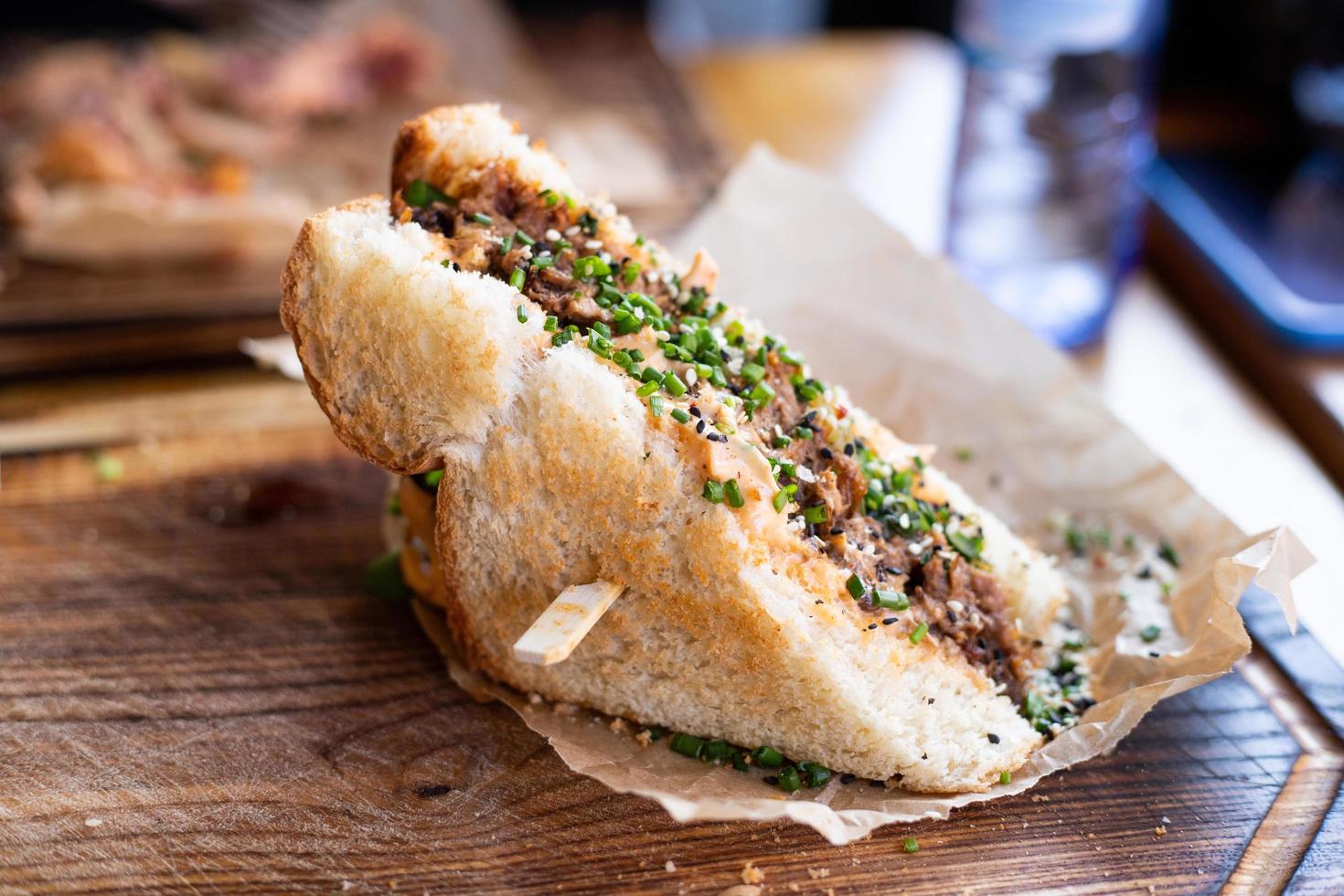 ein knuspriges Sandwich mit Fleisch und anderen Belägen, das auf einem Restauranttisch liegt. foto