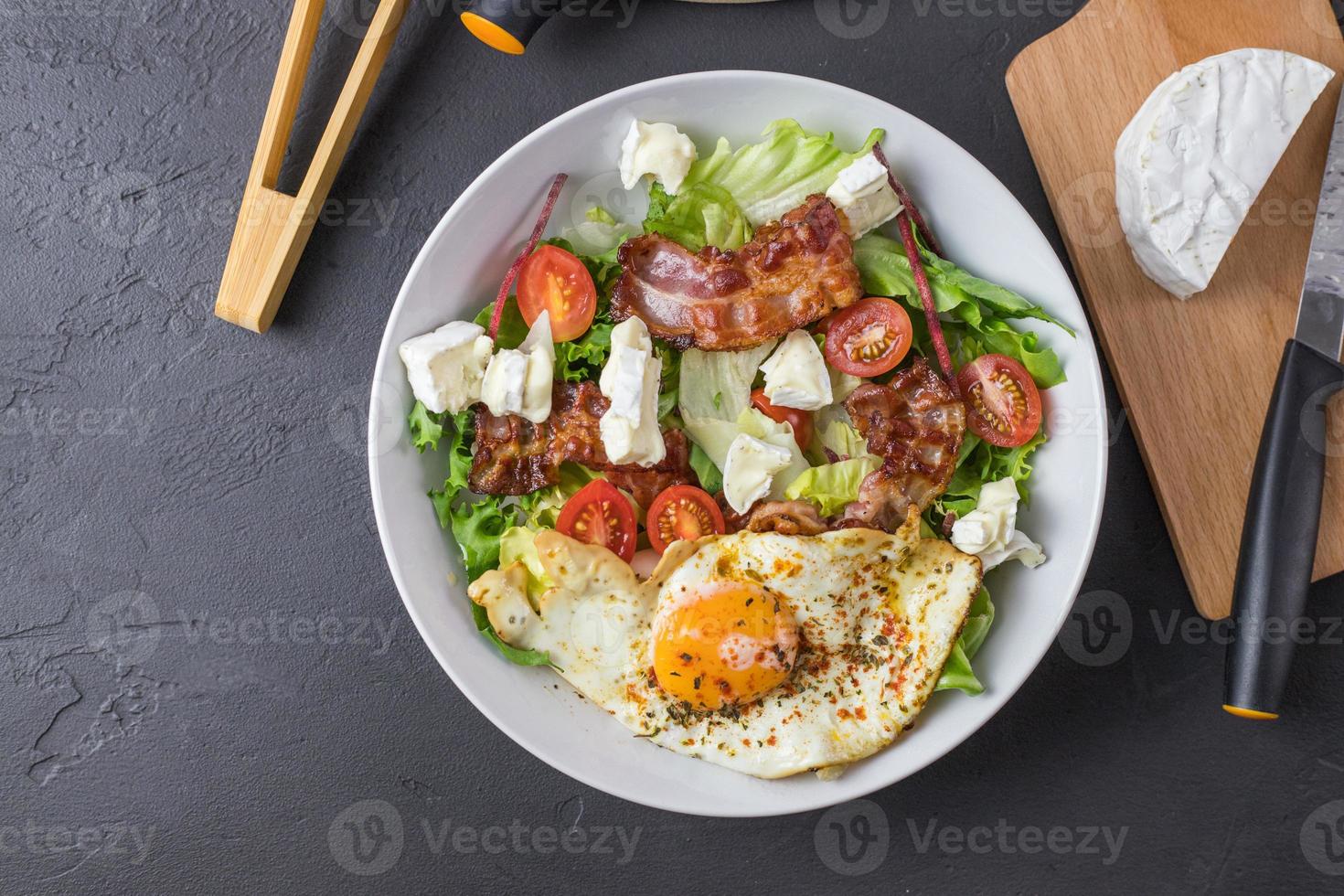 ketogener salat. Spiegelei mit Speck, Tomaten, Blauschimmelkäse und Salat. Rezept für den perfekten Ketosalat. Sicht von oben. foto