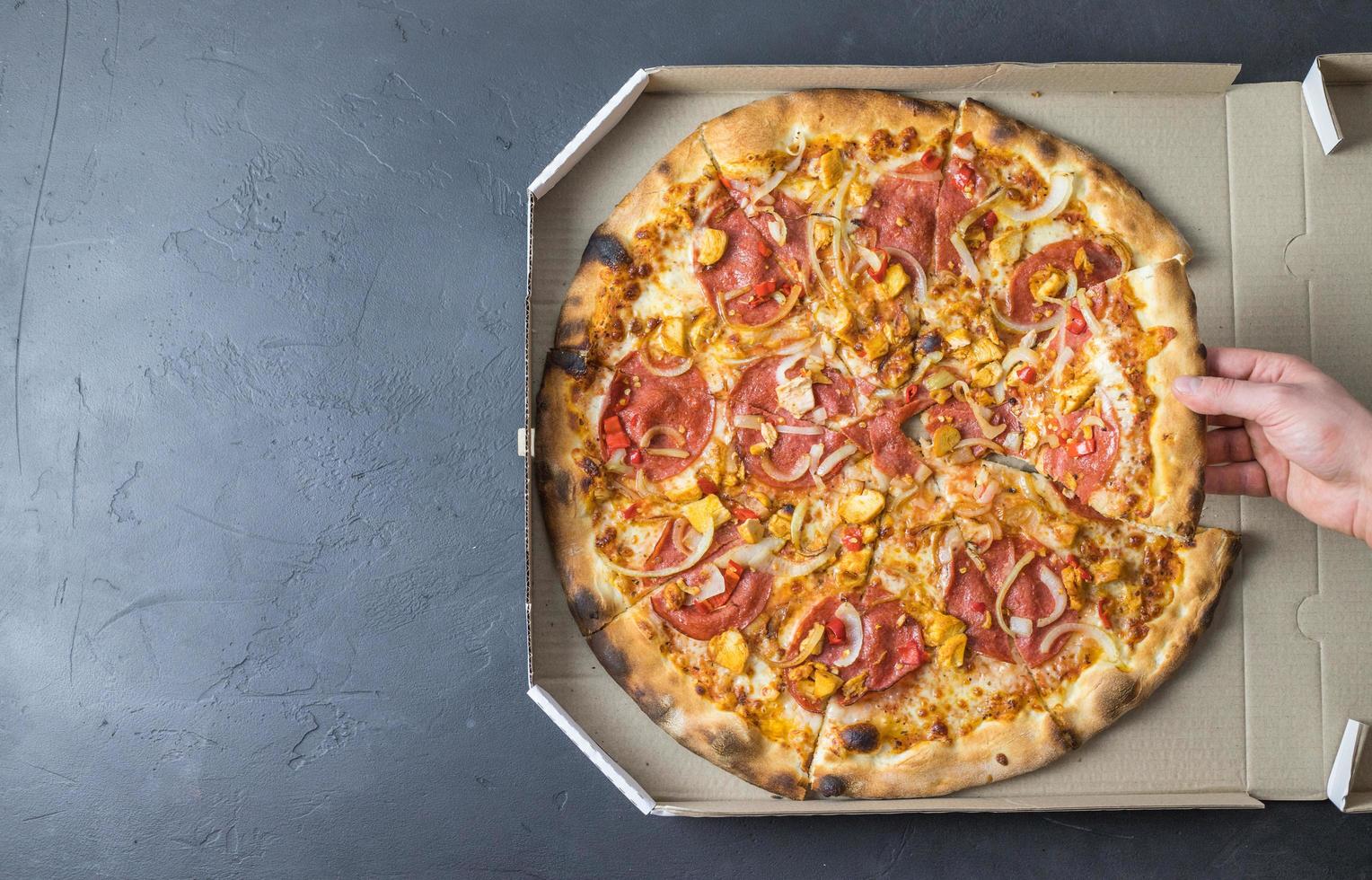 frische Pizza in einer Schachtel auf dunklem Hintergrund. Platz für Text. foto