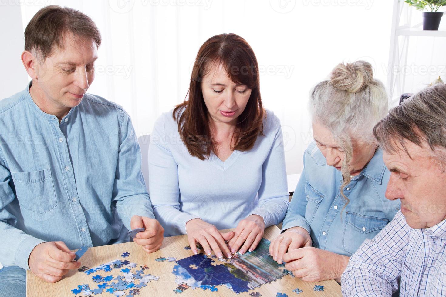 Familie sammelt Puzzle zusammen am Tisch zu Hause foto