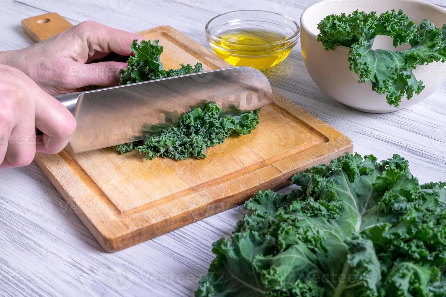 weibliche Hand schneidet Grünkohlblätter mit großem Küchenmesser foto