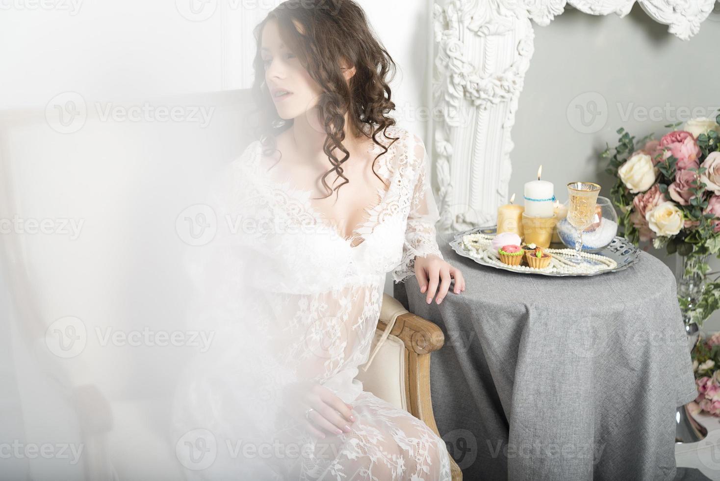 Mädchen in einem weißen Kleid, das an einem Tisch sitzt foto