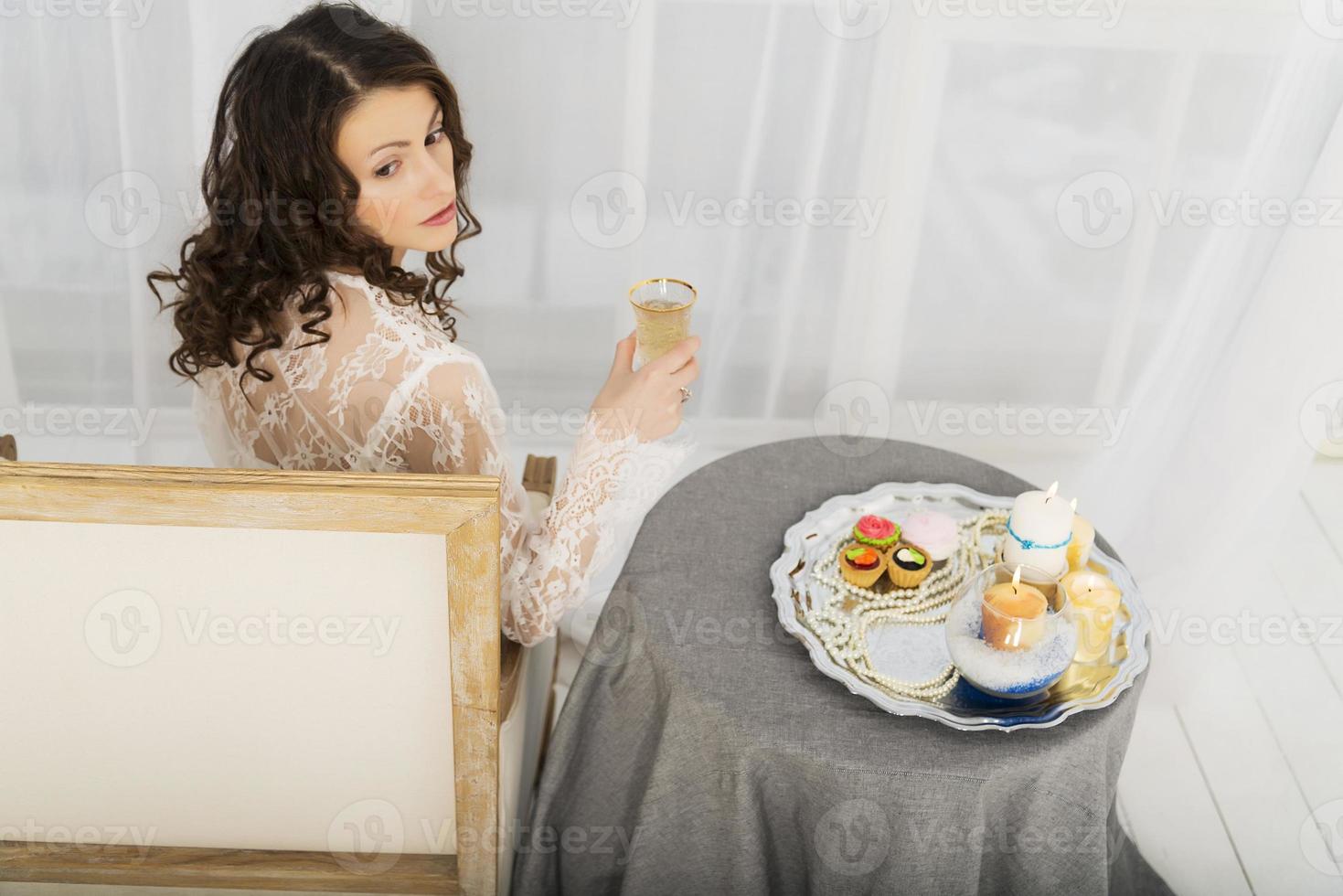 Mädchen in einem weißen Kleid, das an einem Tisch sitzt foto