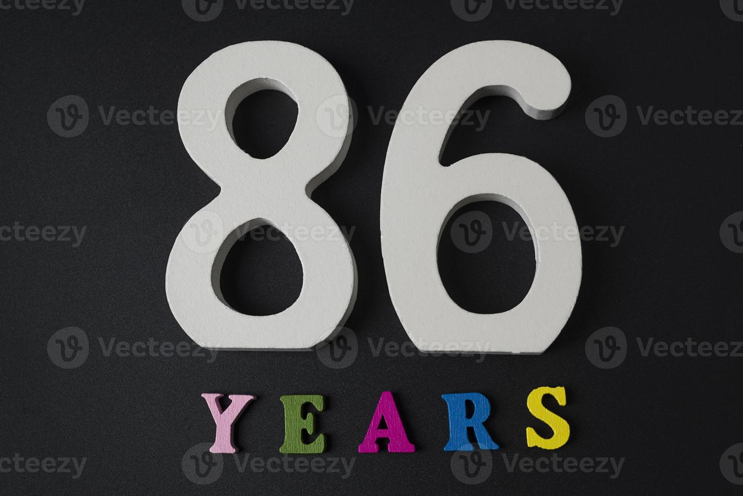 Buchstaben und Zahlen 86 Jahre alt auf schwarzem Hintergrund. foto