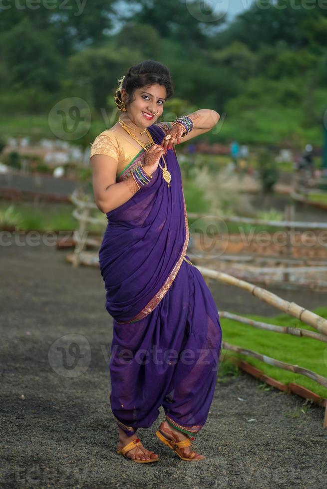 Schönes indisches junges Mädchen im traditionellen Saree posiert im Freien foto