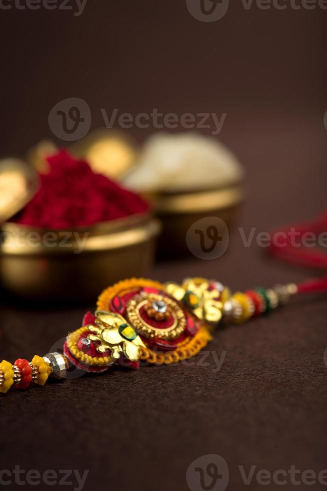 Raksha Bandhan Hintergrund mit einem eleganten Rakhi, Reiskörnern und Kumkum. ein traditionelles indisches Armband, das ein Symbol der Liebe zwischen Brüdern und Schwestern ist. foto