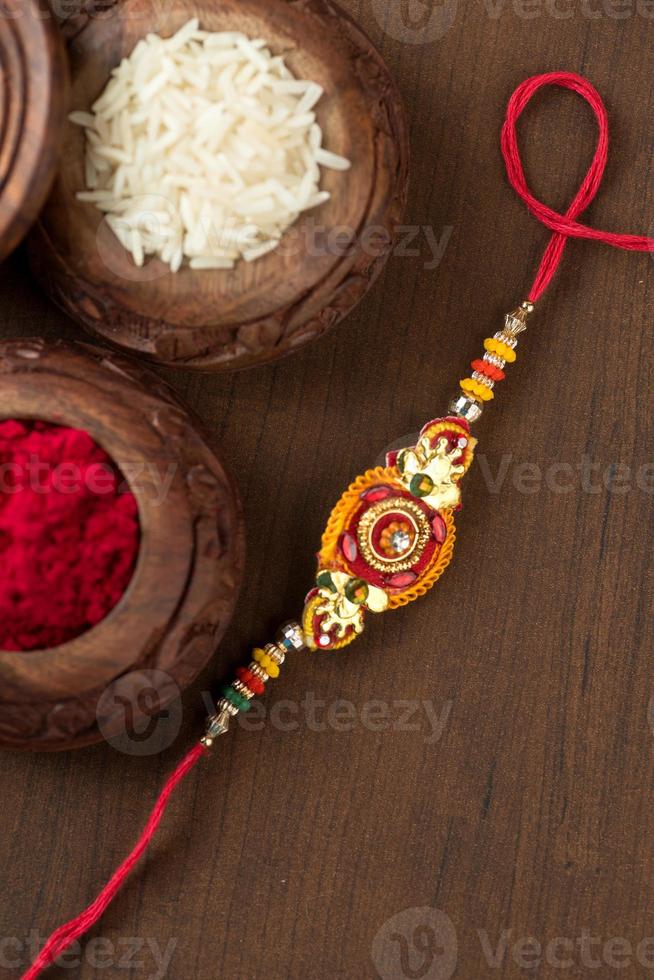 indischer Festival-Raksha-Bandhan-Hintergrund mit einem eleganten Rakhi, Reiskörnern und Kumkum. ein traditionelles indisches Armband, das ein Symbol der Liebe zwischen Brüdern und Schwestern ist. foto