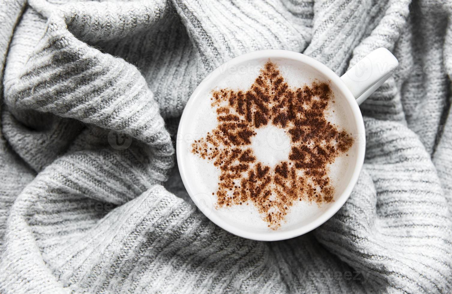 Kaffee mit Schneeflockenmuster auf einem warmen Strickpullover foto