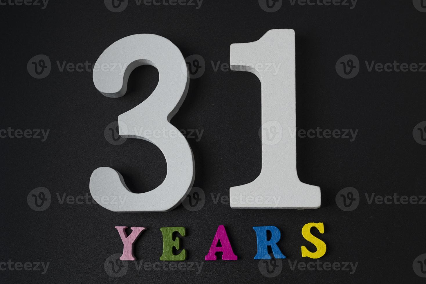 Buchstaben und Zahlen 31 Jahre auf schwarzem Hintergrund. foto