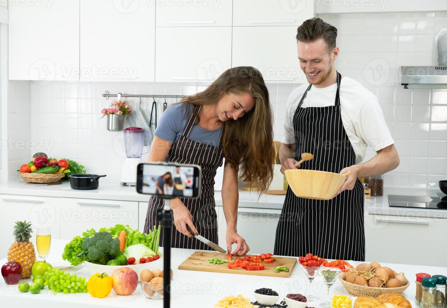 Junges kaukasisches Paar, das Blogger ist und Menschen beibringt, gesundes Essen über die Smartphone-Kamera zu kochen. Familie zusammen Konzept foto