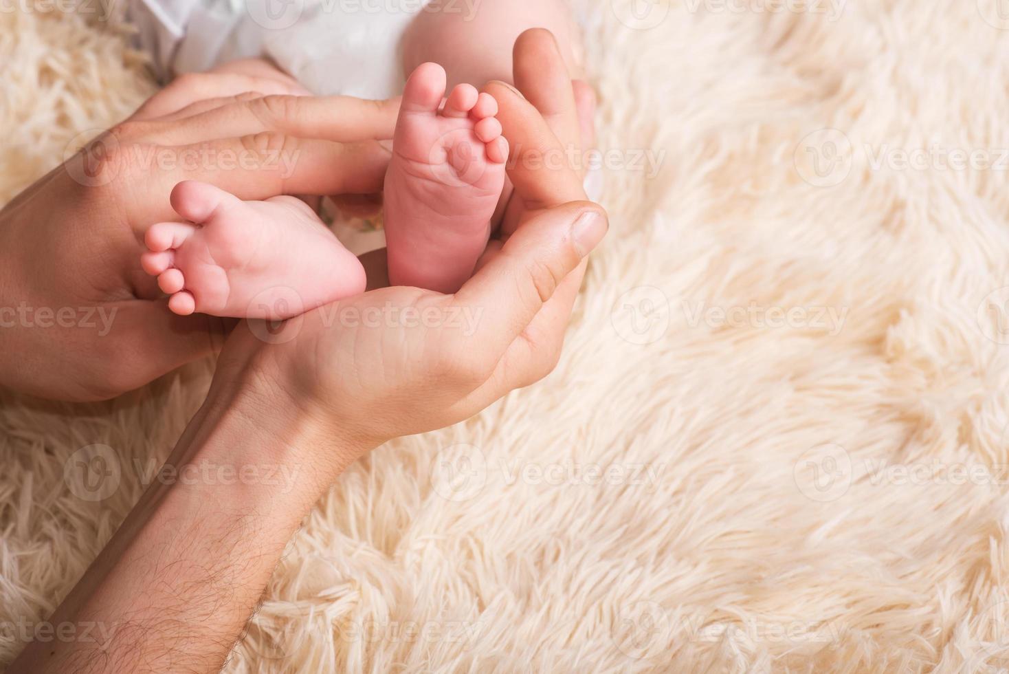 Mama hält in seinen Händen kleine Babyfüße. kleine Beine eines Neugeborenen in den Händen der Mutter. Baby Fußmassage foto