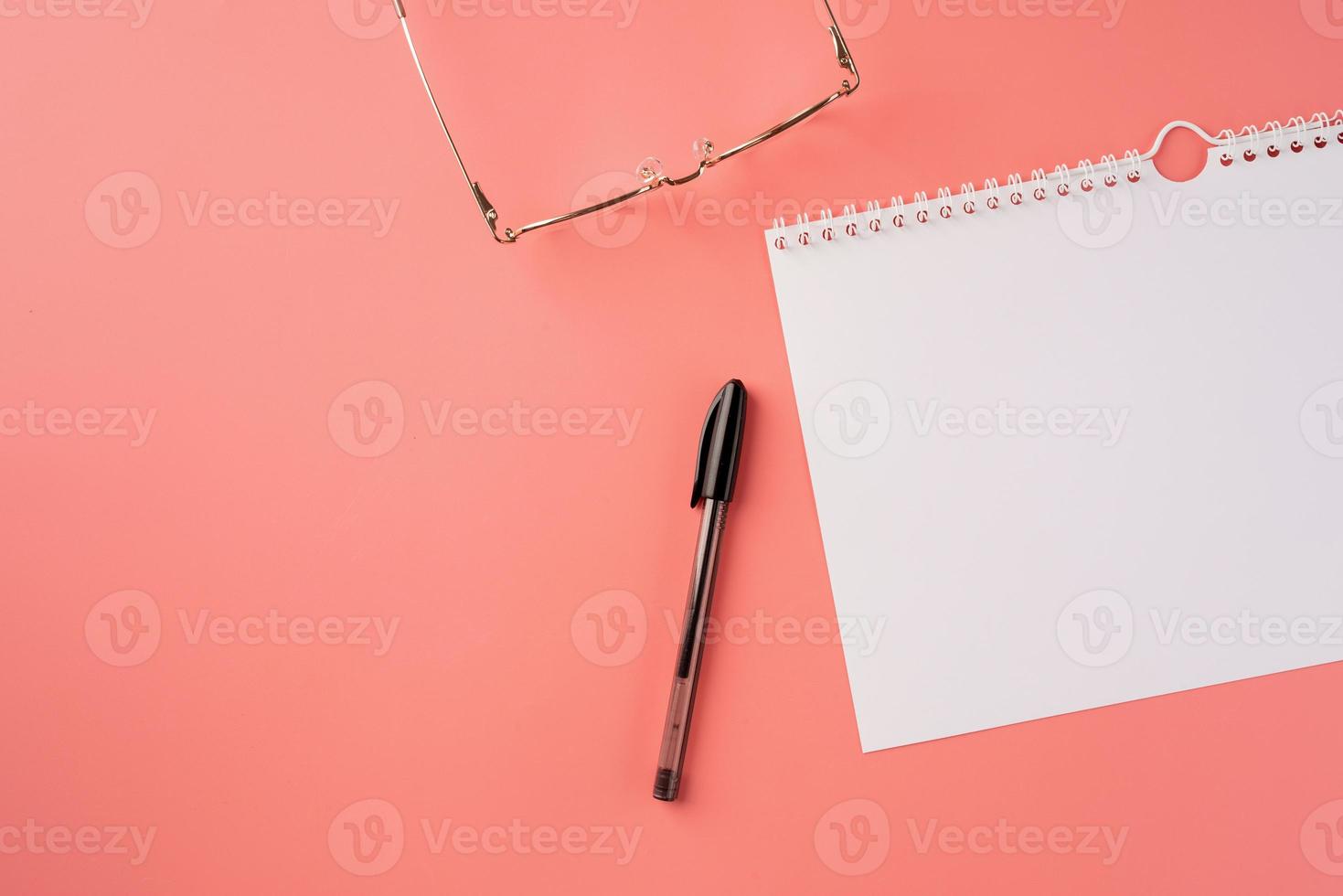 Draufsicht leerer Kalender, Brille und Stift auf rosa Hintergrund foto