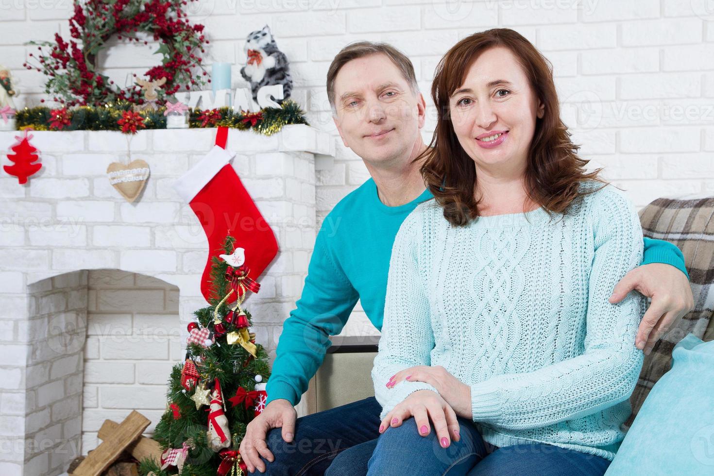 glückliches reifes Paar mittleren Alters, das zu Hause auf dem Sofa sitzt. Weihnachtsfeier, Neujahrsfeiertage foto