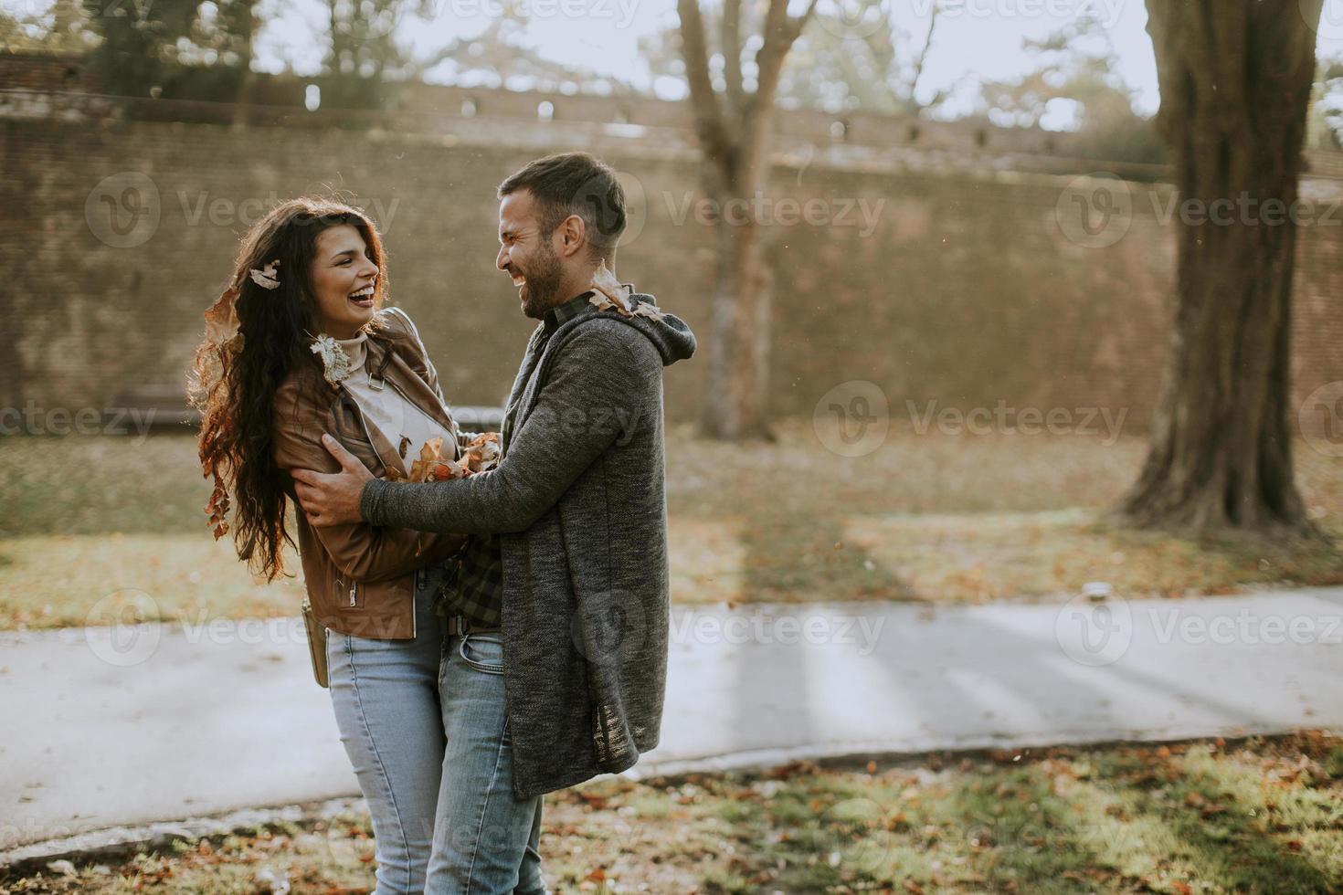 junges Paar, das Spaß mit Herbstlaub im Park hat foto